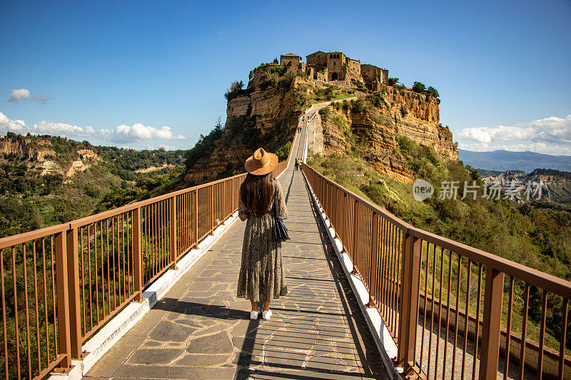 一个年轻女子站在桥上的后视图，Civita di Bagnoregio，意大利